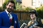 Social Club FM. Image shows from L to R: Mr Chairman (Chris Corcoran), Rex Jones (Elis James). Copyright: Zipline Creative. Social Club FM. Image shows from L to R: Mr Chairman (Chris Corcoran), Rex Jones (Elis James). Copyright: Zipline Creative.