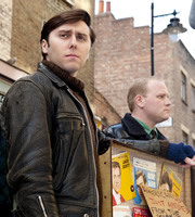 Rock & Chips. Image shows from L to R: Del Boy (James Buckley), Jumbo Mills (Lee Long). Copyright: Shazam Productions / BBC. Rock & Chips. Image shows from L to R: Del Boy (James Buckley), Jumbo Mills (Lee Long). Copyright: Shazam Productions / BBC.