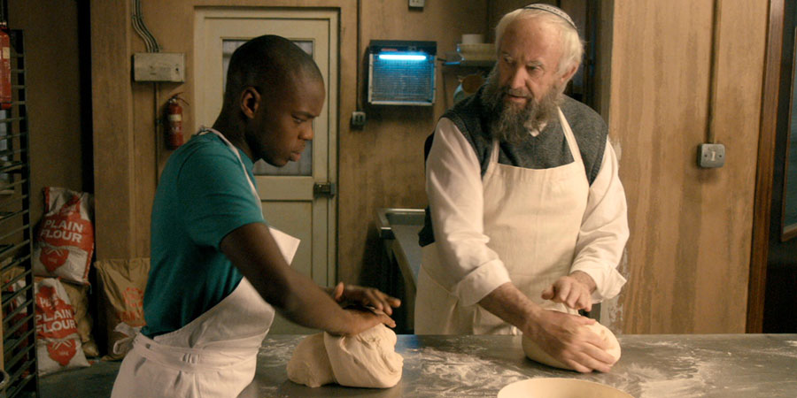 Dough. Image shows from L to R: Ayyash (Jerome Holder), Nat Dayan (Jonathan Pryce). Dough. Image shows from L to R: Ayyash (Jerome Holder), Nat Dayan (Jonathan Pryce).