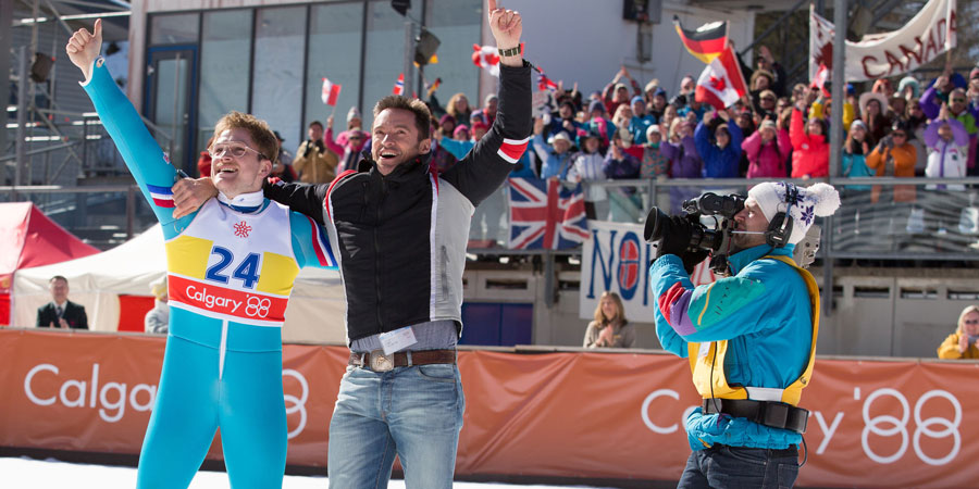 Eddie The Eagle. Image shows from L to R: Michael 'Eddie' Edwards (Taron Egerton), Bronson Peary (Hugh Jackman). Eddie The Eagle. Image shows from L to R: Michael 'Eddie' Edwards (Taron Egerton), Bronson Peary (Hugh Jackman).