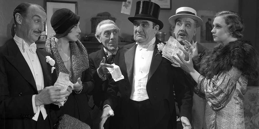 Money Talks. Image shows from L to R: Solly Sax (Gus McNaughton), Rosie Pilstein (Judy Kelly), Unknown, Abe Pilstein of Magenta Street (Julian Rose), Joe Bell (Jimmy Godden), Nellie B. Kelly (Mary Charles). Copyright: Studio Canal. Money Talks. Image shows from L to R: Solly Sax (Gus McNaughton), Rosie Pilstein (Judy Kelly), Unknown, Abe Pilstein of Magenta Street (Julian Rose), Joe Bell (Jimmy Godden), Nellie B. Kelly (Mary Charles). Copyright: Studio Canal.