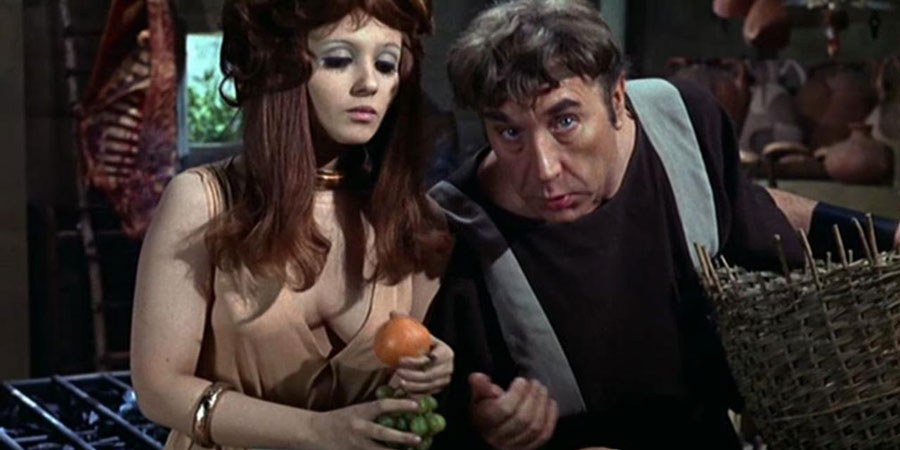 Up Pompeii. Image shows from L to R: Scrubba (Adrienne Posta), Lurcio (Frankie Howerd). Copyright: STUDIOCANAL. Up Pompeii. Image shows from L to R: Scrubba (Adrienne Posta), Lurcio (Frankie Howerd). Copyright: STUDIOCANAL.