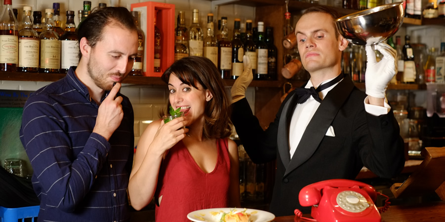 Foreigners. Image shows from L to R: Greg (Tommy Love), Josephine (Nathalie Codsi), Waiter (Stuart Walker). Foreigners. Image shows from L to R: Greg (Tommy Love), Josephine (Nathalie Codsi), Waiter (Stuart Walker).