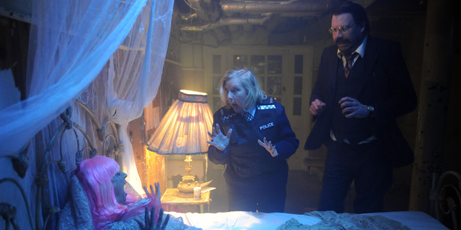 Murder In Successville. Image shows from L to R: Deborah Meaden, DI Sleet (Tom Davis). Copyright: Tiger Aspect Productions. Murder In Successville. Image shows from L to R: Deborah Meaden, DI Sleet (Tom Davis). Copyright: Tiger Aspect Productions.