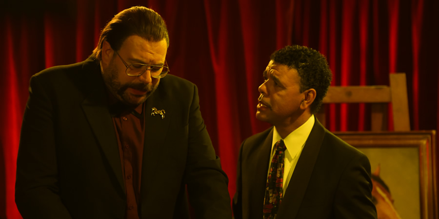 Murder In Successville. Image shows from L to R: DI Sleet (Tom Davis), Chris Kamara. Copyright: Tiger Aspect Productions. Murder In Successville. Image shows from L to R: DI Sleet (Tom Davis), Chris Kamara. Copyright: Tiger Aspect Productions.