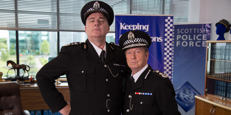 Scot Squad. Image shows from L to R: Chief Commissioner Cameron Miekelson (Jack Docherty), Sir Neville Archibald (Bill Paterson). Copyright: The Comedy Unit. Scot Squad. Image shows from L to R: Chief Commissioner Cameron Miekelson (Jack Docherty), Sir Neville Archibald (Bill Paterson). Copyright: The Comedy Unit.