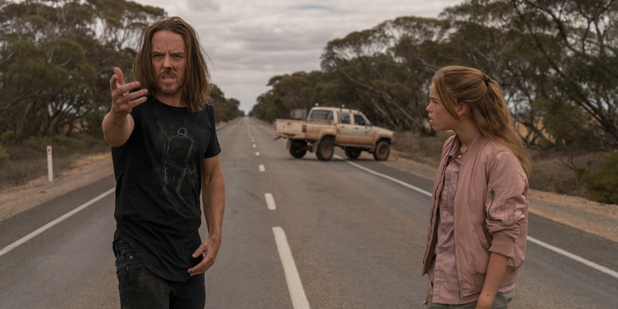 Upright. Image shows from L to R: Lucky Flynn (Tim Minchin), Meg Adams (Milly Alcock). Upright. Image shows from L to R: Lucky Flynn (Tim Minchin), Meg Adams (Milly Alcock).