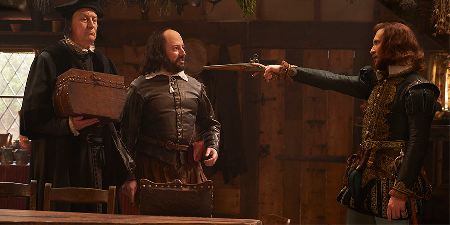 Upstart Crow. Image shows from L to R: Hunt (Geoffrey Whitehead), Will Shakespeare (David Mitchell), Marlowe (Tim Downie). Copyright: BBC. Upstart Crow. Image shows from L to R: Hunt (Geoffrey Whitehead), Will Shakespeare (David Mitchell), Marlowe (Tim Downie). Copyright: BBC.