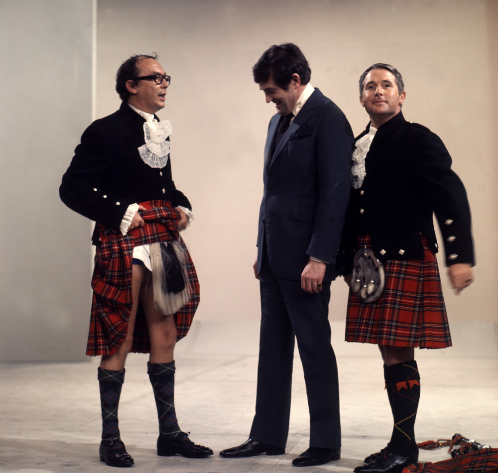 Eric Morecambe in kilt showing Derek Nimmo what he's wearing underneath and Ernie Wise in a kilt. Copyright: BBC History. Eric Morecambe in kilt showing Derek Nimmo what he's wearing underneath and Ernie Wise in a kilt. Copyright: BBC History.