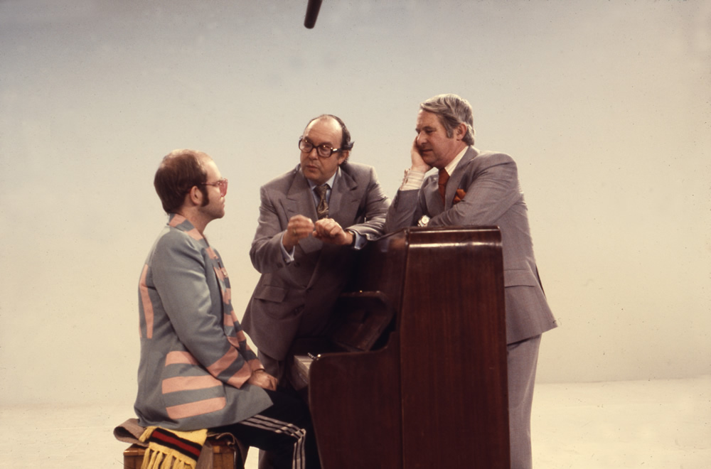 Elton John sat at piano and Eric Morecambe and Ernie Wise, 25/12/1976. Copyright: BBC History. Elton John sat at piano and Eric Morecambe and Ernie Wise, 25/12/1976. Copyright: BBC History.