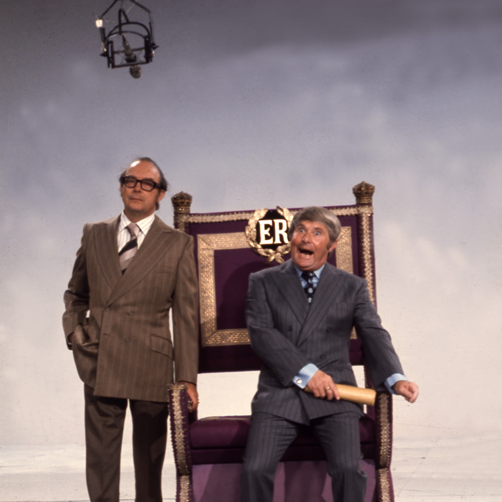 Eric Morecambe standing and Ernie Wise sat on throne, 27/09/1974. Image shows from L to R: Eric Morecambe, Ernie Wise. Copyright: BBC History. Eric Morecambe standing and Ernie Wise sat on throne, 27/09/1974. Image shows from L to R: Eric Morecambe, Ernie Wise. Copyright: BBC History.